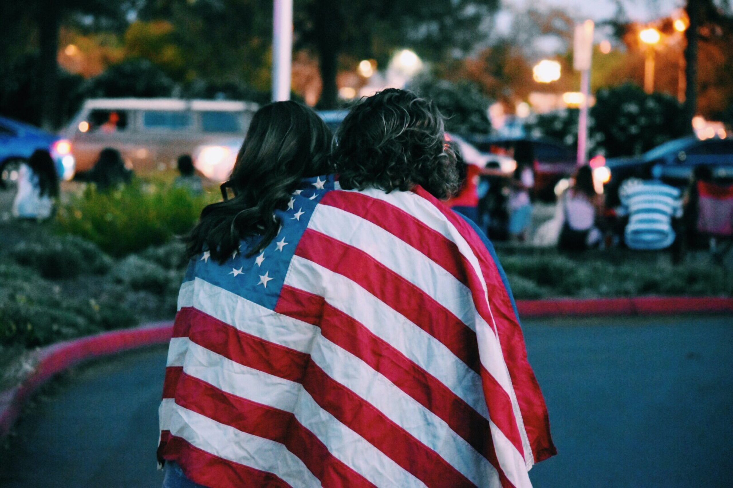 Two women embrace while draped in the American flag