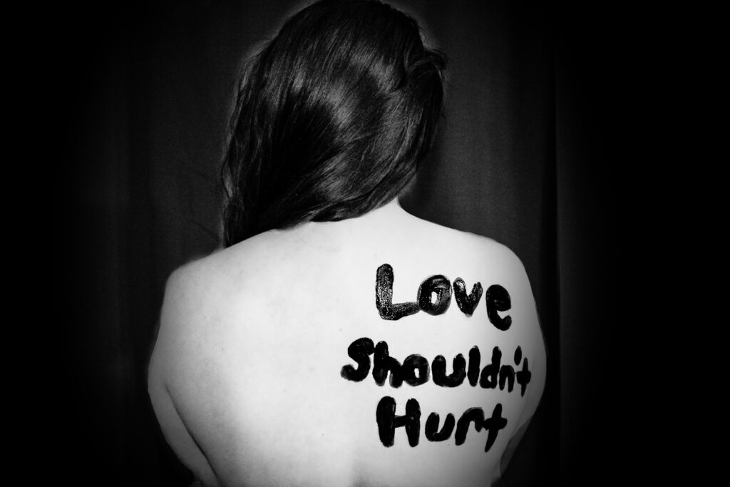 Photo of person with "Love shouldn't hurt" written on their back in marker