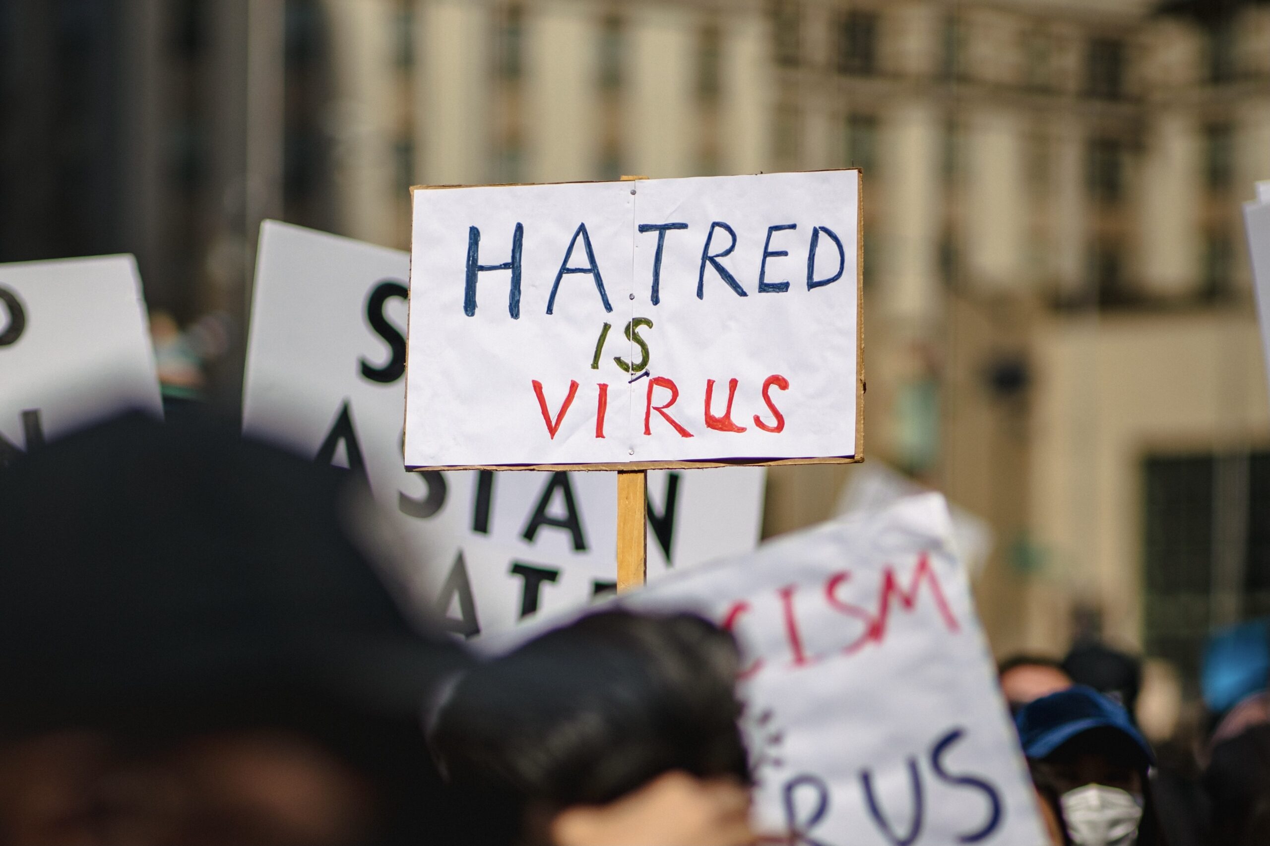 Person holding sign "Hatred is a virus"
