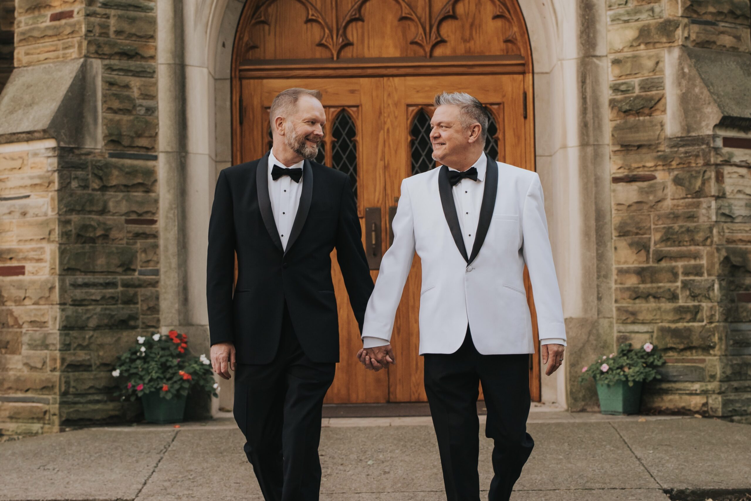 Grooms in tuxes walking on campus on their wedding day